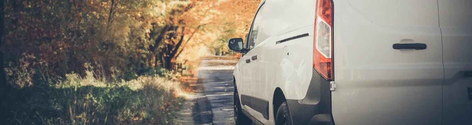 Van parked on verge of autumnal scenic road