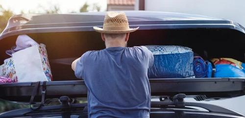 Person packing travel essentials into vehicle roof-box