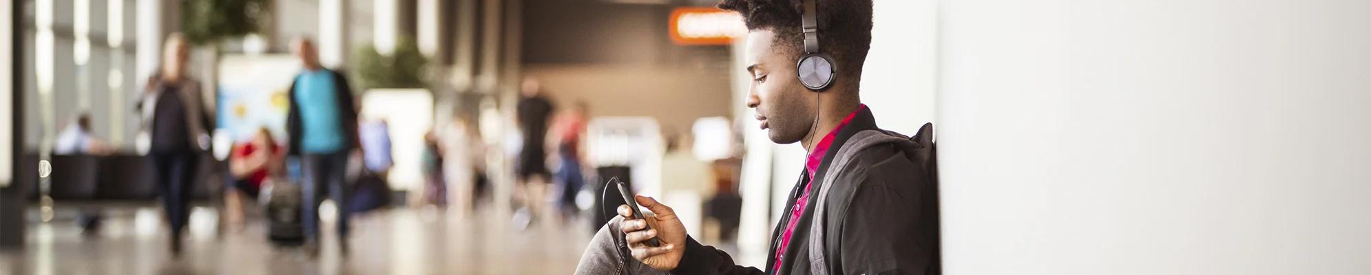 Young person with headphones on and looking at mobile phone