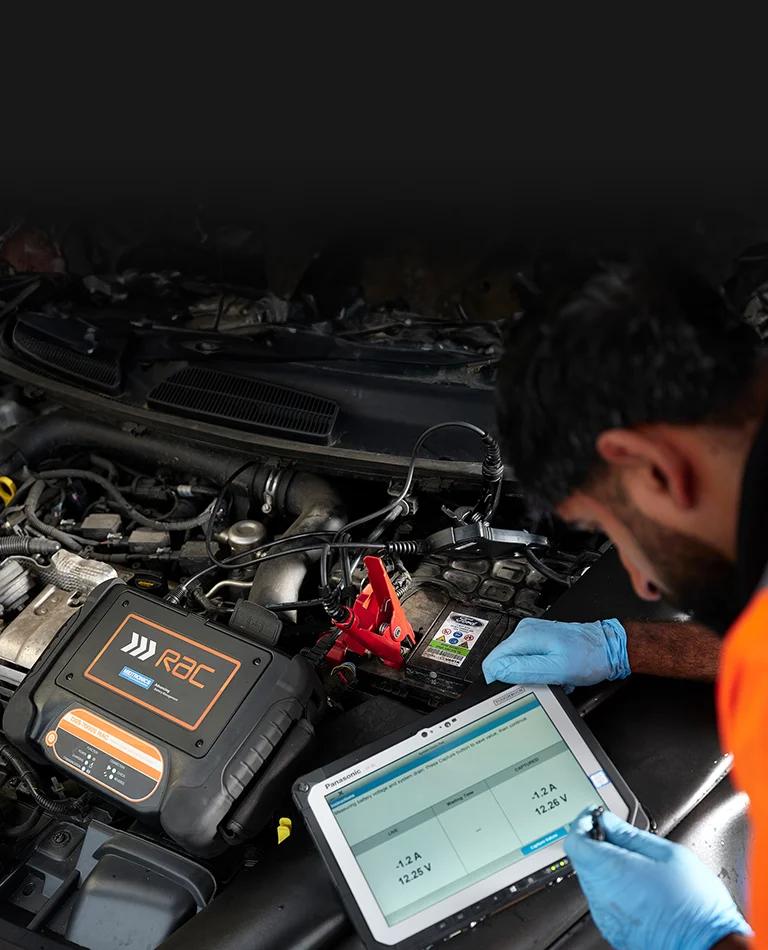 An RAC Mobile Mechanic using a diagnostic machine inspecting a car for an alternator repair.