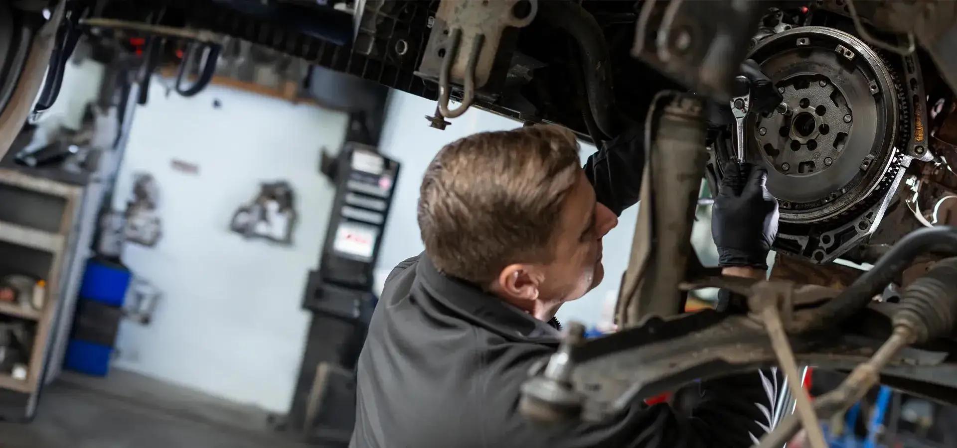 A mechanic under a car that has been raised up on vehicle bay.