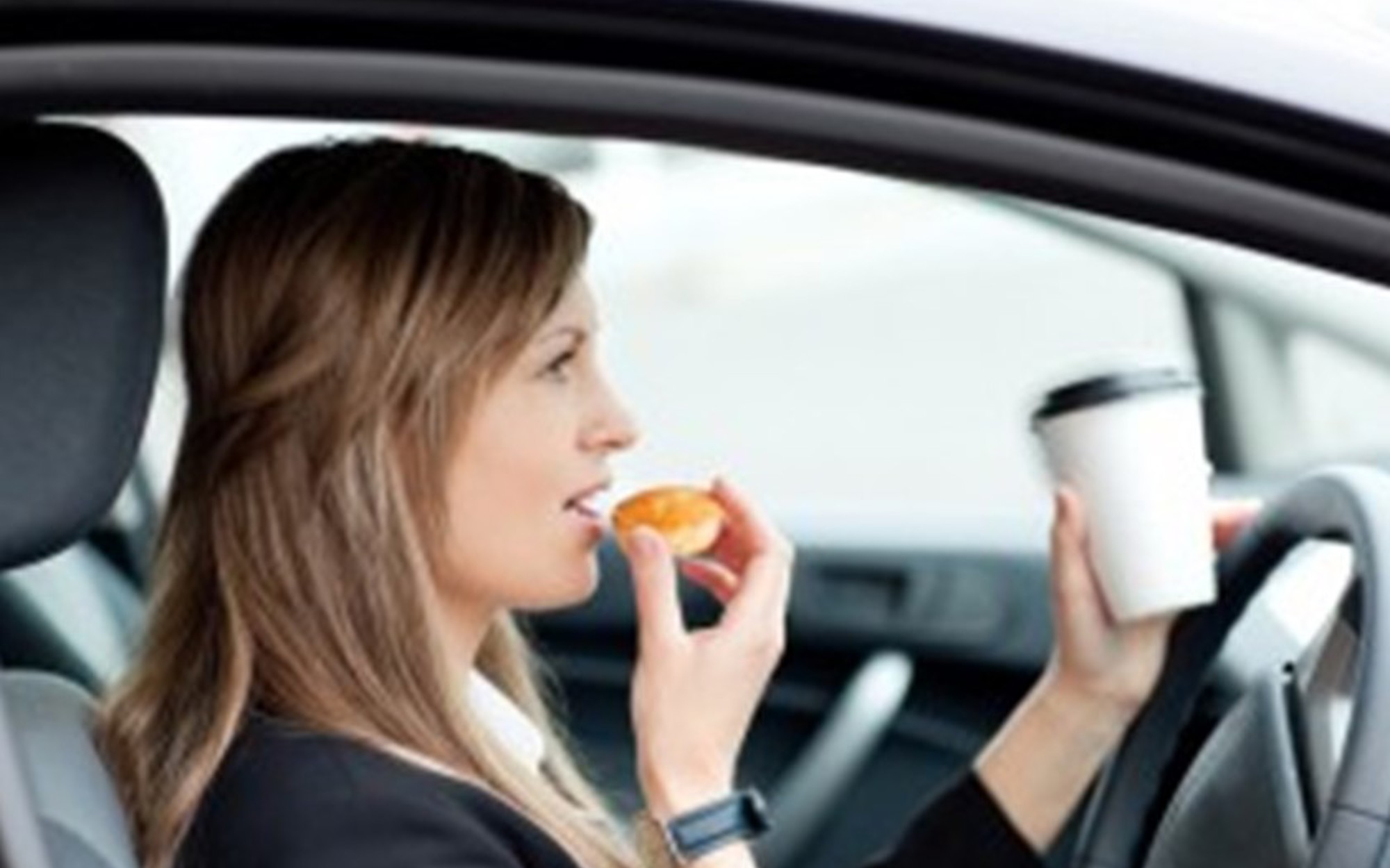 Woman eating and drinking while driving a car